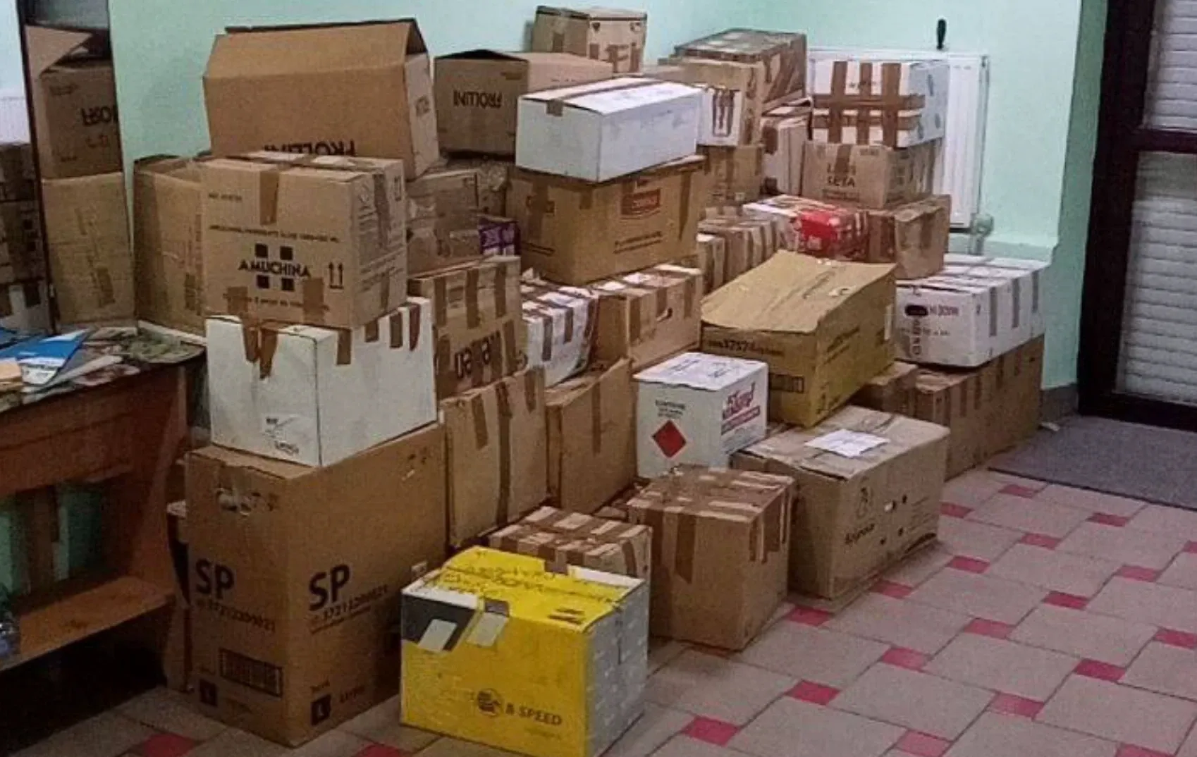 Кімната, заставлена картонними коробками з гуманітарною допомогою під саму стелю.